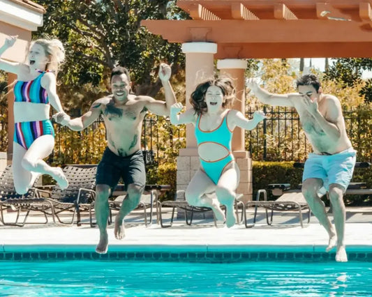 A group of young men and women are jumping into the pool